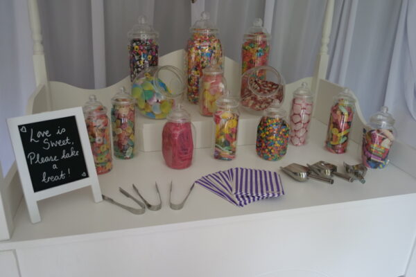 Close up image of sweet jars on a white wooden sweet cart.