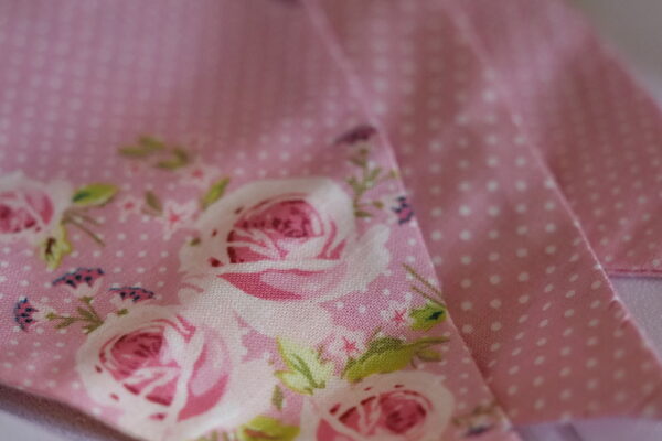 Pink polka dot material triangular bunting with pink rose floral pattern