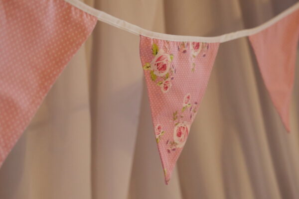 Pink polka dot material triangular bunting with pink rose floral pattern